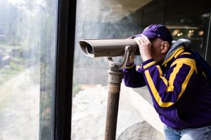 Man looking through mounted binoculars at the Como Zoo