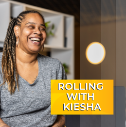 Photo of Kiesha laughing at the Lifeworks office. An orange and yellow box has peen placed over the image with text reading: Rolling with Kiesha"