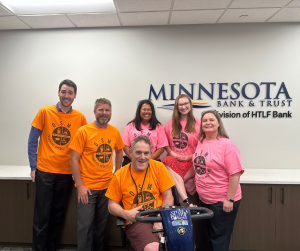 Photo of Michael with the staff at Minnesota Bank and Trust, a division of HTLF Bank. They are all wearing the Disabled Speech Matters t-shirts that Michael designed.