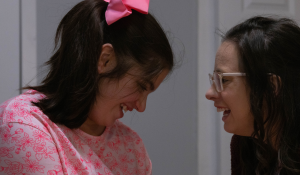 A close up photo of Lydia, on the left, and Addyson, on the right, smiling at each other.